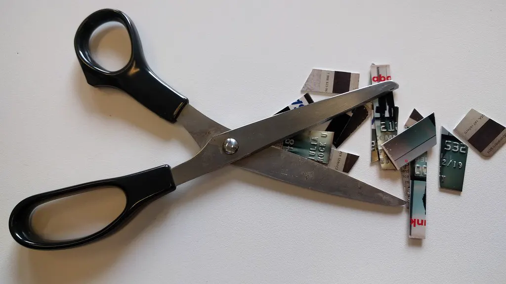 A pair of scissors beside the cut-up pieces of a credit card