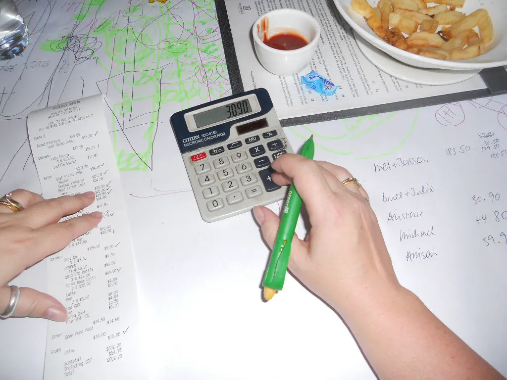 Hands with a pen and calculator checking a long receipt