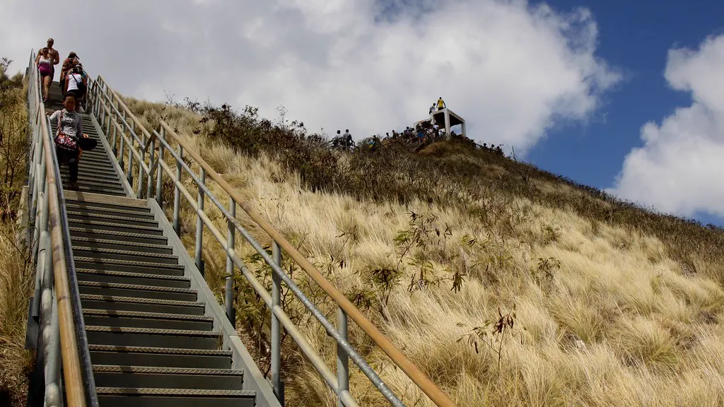 People climbing a long outdoor staircase up a grassy hill
