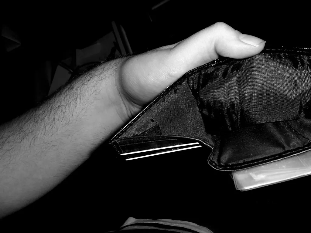 A hand holding open an empty black wallet