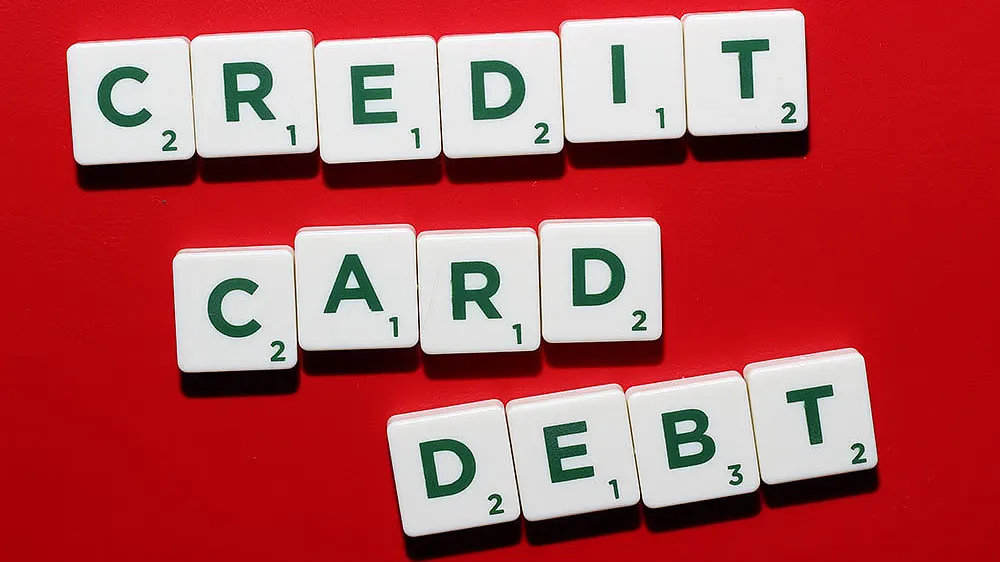Letter tiles spelling “credit card debt” on a red background