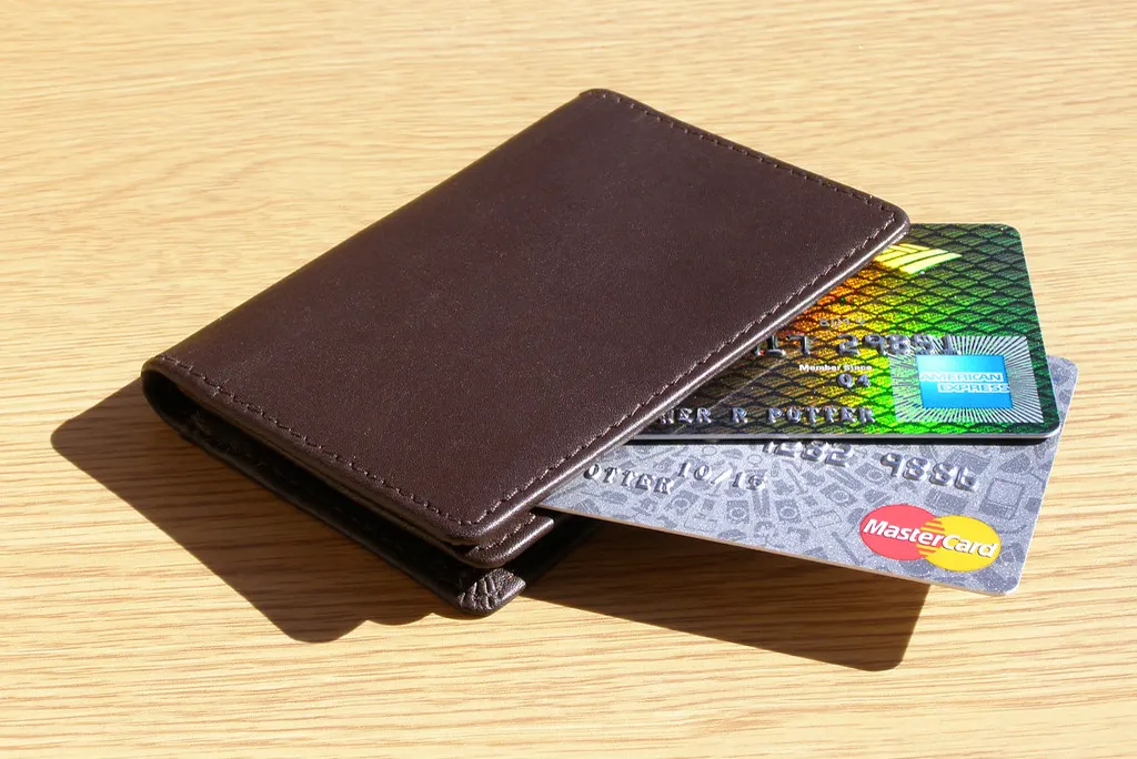 Credit cards tucked into a brown leather wallet on a wooden table